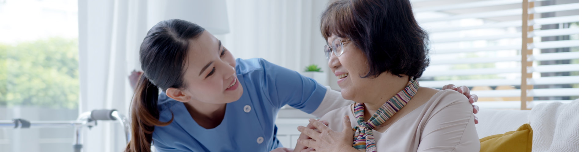 A female caregiver and an elderly woman facing each other