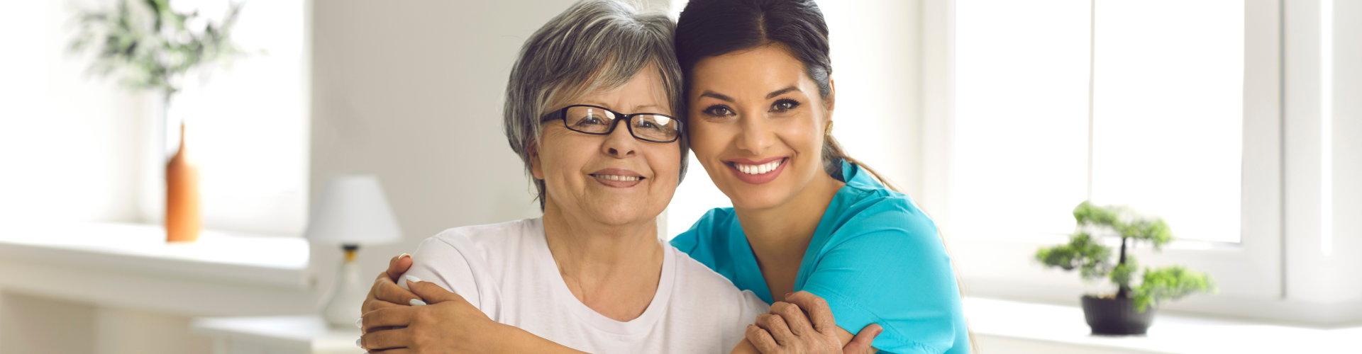 Female caregiver and an elderly woman smiling