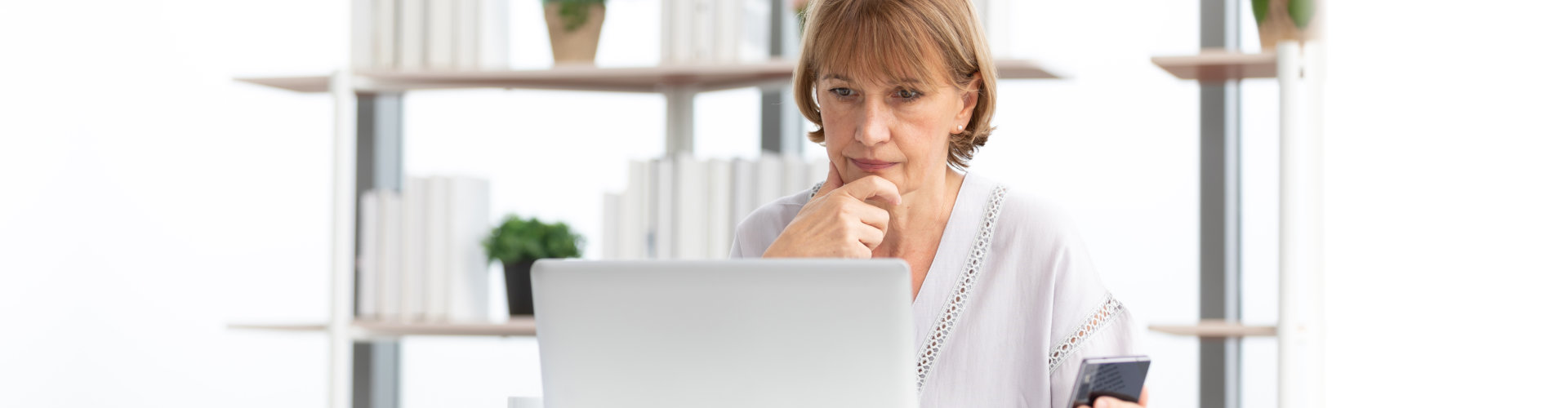 An elderly woman using laptop and her mobile phone